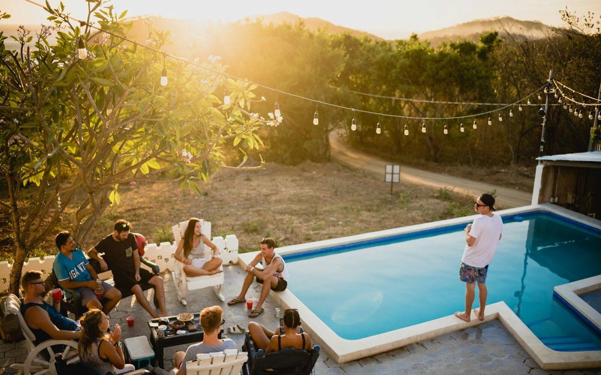 A garden full of people at golden hour, string lights strung between the trees.