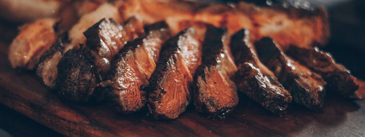 A smoked beef cut carved into thick slices, dark bark on every edge.